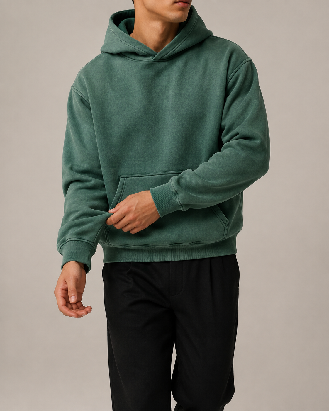 Front studio view of the TELLS Evergreen Washed Hoodie in Dark Green, styled with black trousers.