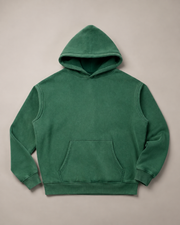 Flat-lay studio view of the plain TELLS Evergreen Washed Hoodie in Dark Green, with a drawstring-free hood and kangaroo pocket.
